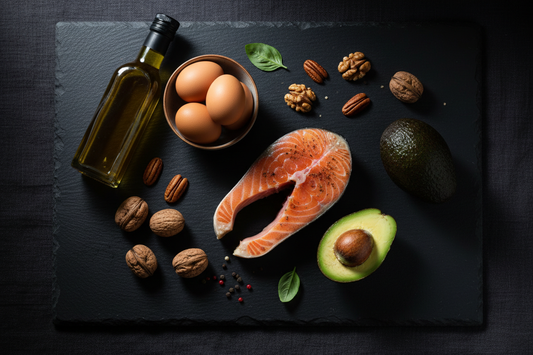 Flat lay med hälsosamma fettkällor – lax, avokado, valnötter, olivolja och ägg på svart yta